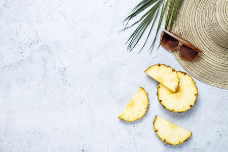 Women's hat, sunglasses, pineapple slices, palm leaf on a concrete background. Top view, flat lay.の写真素材