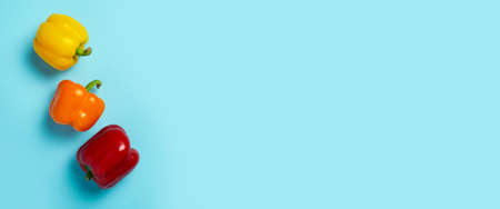 Three fresh bright sweet peppers on a blue background. Top view, flat lay. Banner.