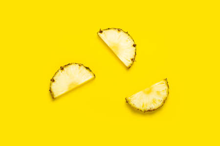 Ripe pineapple slices on a yellow background. Top view, flat lay.の写真素材