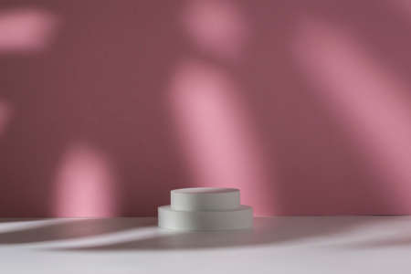 White podiums for presentation and shadow of monstera leaf on white pink background.の写真素材