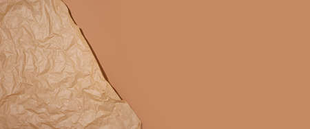 Crumpled craft paper on a brown cardboard background. Banner.の写真素材