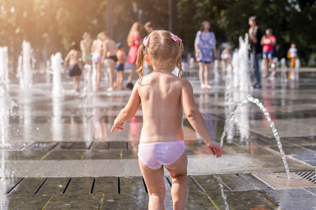 Cute little girl playing on urban jet fountains with splashing water.の写真素材