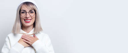 Cheerful young woman in glasses in a hoodie on a light background.の写真素材