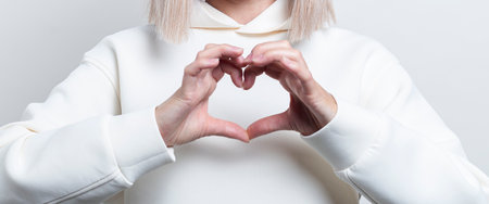 Female hands show a heart gesture on a light background. Banner.の写真素材