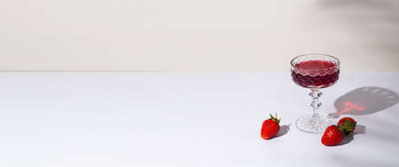 glass with red wine and strawberries on the table on a light background. Top view, flat lay. Banner.の写真素材