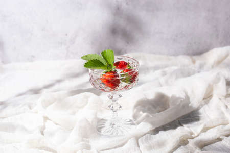 Fresh juicy strawberries in a glass on a light fabric background.の写真素材