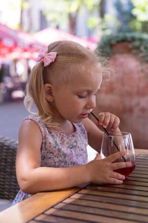 Child drinks a drink on the summer terrace under natural light. Real people.の写真素材