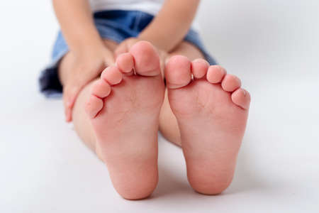 Bare feet of a child in the studio on a light background.の写真素材