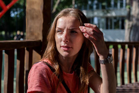 Young woman looking to the side straightens hair on a sunny day.の写真素材