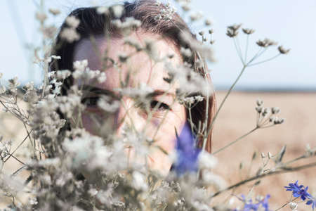 Young woman with a bouquet of wild flowers in the field