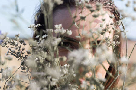 Young woman looking through a bouquet of wildflowers on the field