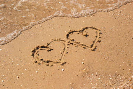 Two hearts drawn on a sandy beach. Top view, flat lay.の写真素材