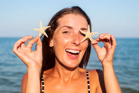 Smiling young woman with starfish on the background of the sea.の写真素材