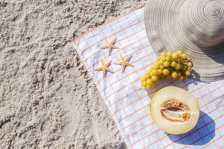Half a melon, grapes, starfish on the beach. Top view, flat lay.の写真素材