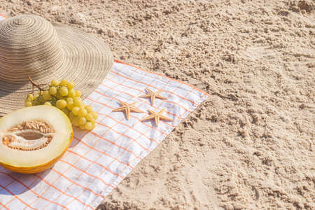 Half a melon, grapes, starfish on the beach. Top view, flat lay.の写真素材