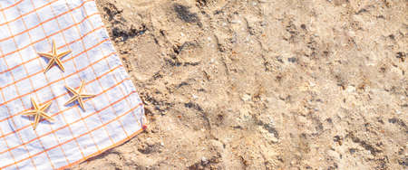 Golden starfish on a bedspread on a sandy beach. Top view, flat lay. Banner.の写真素材