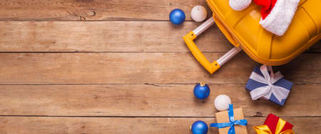 Yellow suitcase on a wooden background. Concept for Christmas, New Year. Top view, flat lay. Banner.の写真素材
