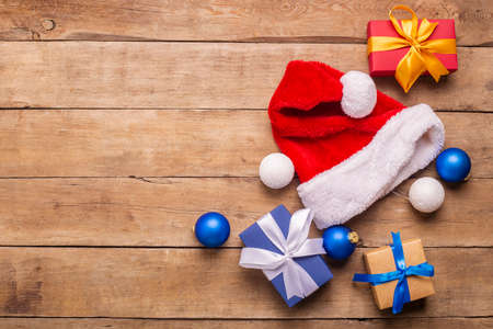 Santa Claus hat and gifts on a wooden background. Concept for Christmas, New Year. Top view, flat lay.の写真素材
