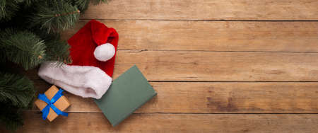 Book and hat of Santa Claus on a wooden background. Top view, flat lay. Banner.の写真素材
