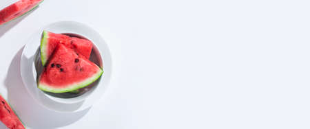 Slices of ripe watermelon on a plate on a white table. Top view, flat lay. Banner.