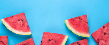 Slices of juicy watermelon on a blue background. Top view, flat lay. Banner.の写真素材