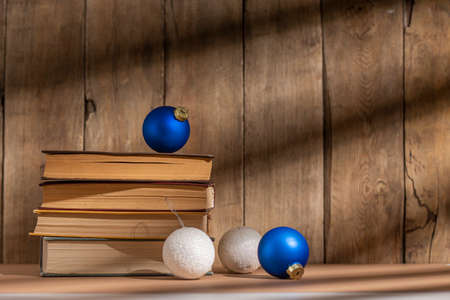 Stack of books and christmas tree decorations on wooden background.の写真素材