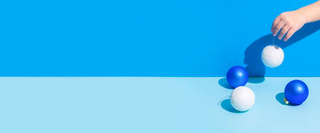 Abstract image hand holds Christmas-tree decorations on a blue background. Banner