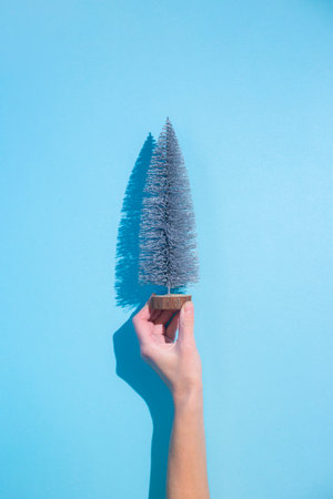 Hand holds a decorative Christmas tree on a blue background. Bannerの写真素材