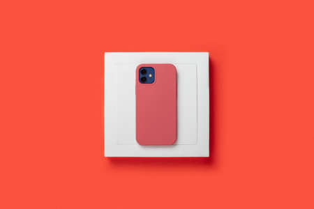 Phone in a case on a pedestal on a red background. Top view, flat lay.