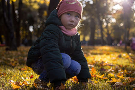 Child girl in a hat in an autumn park on a sunny dayの写真素材