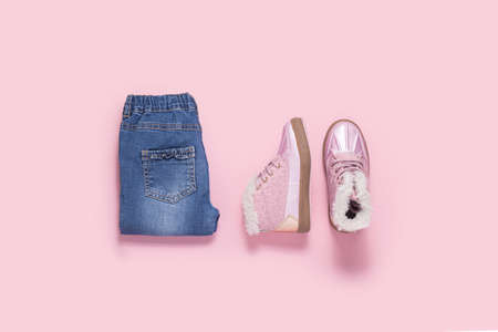 Boots and blue jeans for a girl on a pink background. Top view, flat layの写真素材