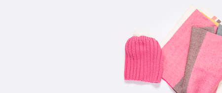 Pink hat and striped scarf on a white background. Top view, flat lay. Bannerの写真素材