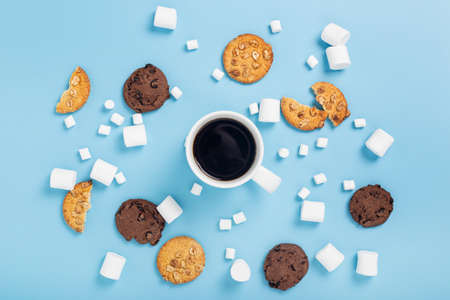 Cup of coffee, marshmallow, cookies on a blue background. Top view, flat layの写真素材
