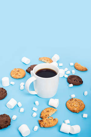 Cup of coffee, marshmallow, cookies on a blue backgroundの写真素材