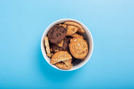 Cookies in a white bowl on a blue background. Top view, flat lay