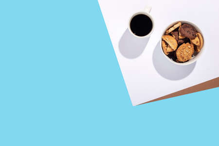 Cup with coffee, cookies in a bowl on a white-blue background. Top view, flat layの写真素材
