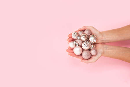 In women's palms, decorative pink shiny balls on a pink background. Top view, flat layの写真素材