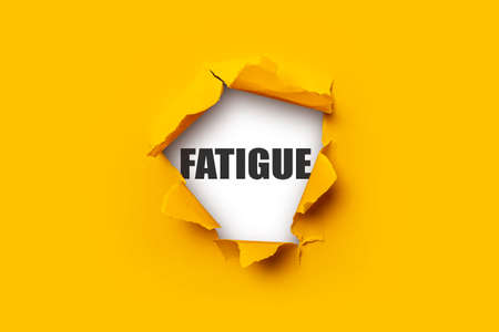 Bright yellow torn paper inside in a hole the inscription Fatigue on a white backgroundの写真素材