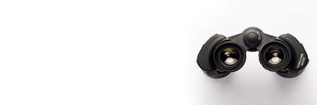Binoculars on a light white background. Banner. Flat lay, top view.