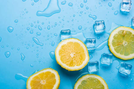 juicy fresh yellow lemon slices and ice cubes on a blue background. Top view, flat lay.の写真素材