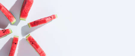 Slices of ripe watermelon lie on a white background. Top view, flat lay. Banner.