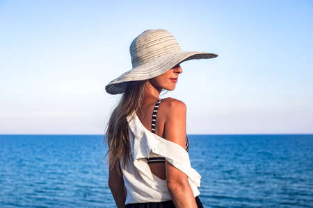 Young sexy woman in hat on blue sky background
