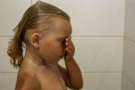 Child girl with closed eyes with wet hair takes a shower