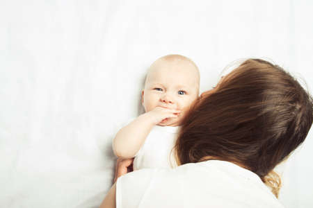 Little baby with mom on a bed with a white sheet. Flat lay, top view.の写真素材
