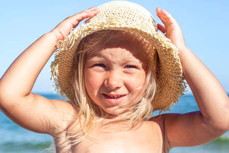 Cheerful child girl in Panama hat on the beach on a sunny day