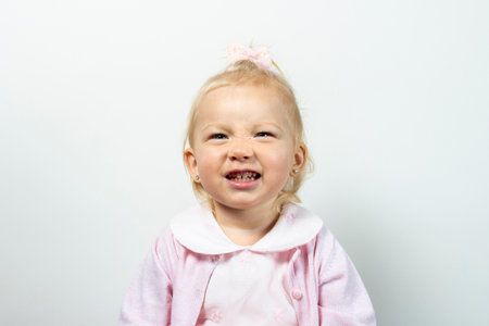 Little kid girl in dress grimaces on a light background.の写真素材
