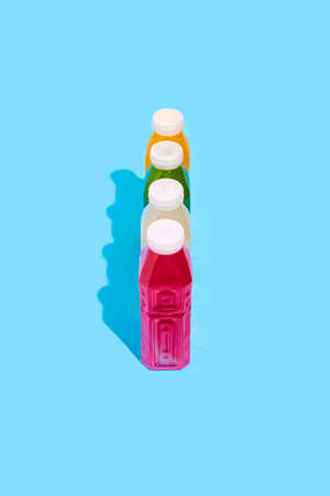 Colored detox drink in plastic bottles on a blue background. top view, flat lay