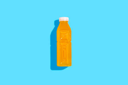 Yellow detox juice drink in a bottle on a blue background. top view, flat layの写真素材