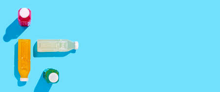 Colored detox drink in plastic bottles on a blue background. Top view, flat lay. Bannerの写真素材
