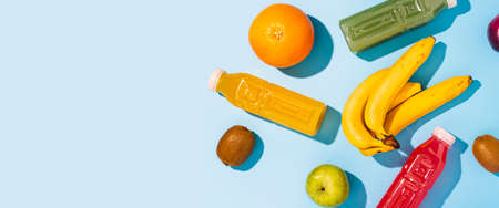 Fruits, juices detox in plastic bottles on a blue background. Top view, flat lay. Banner